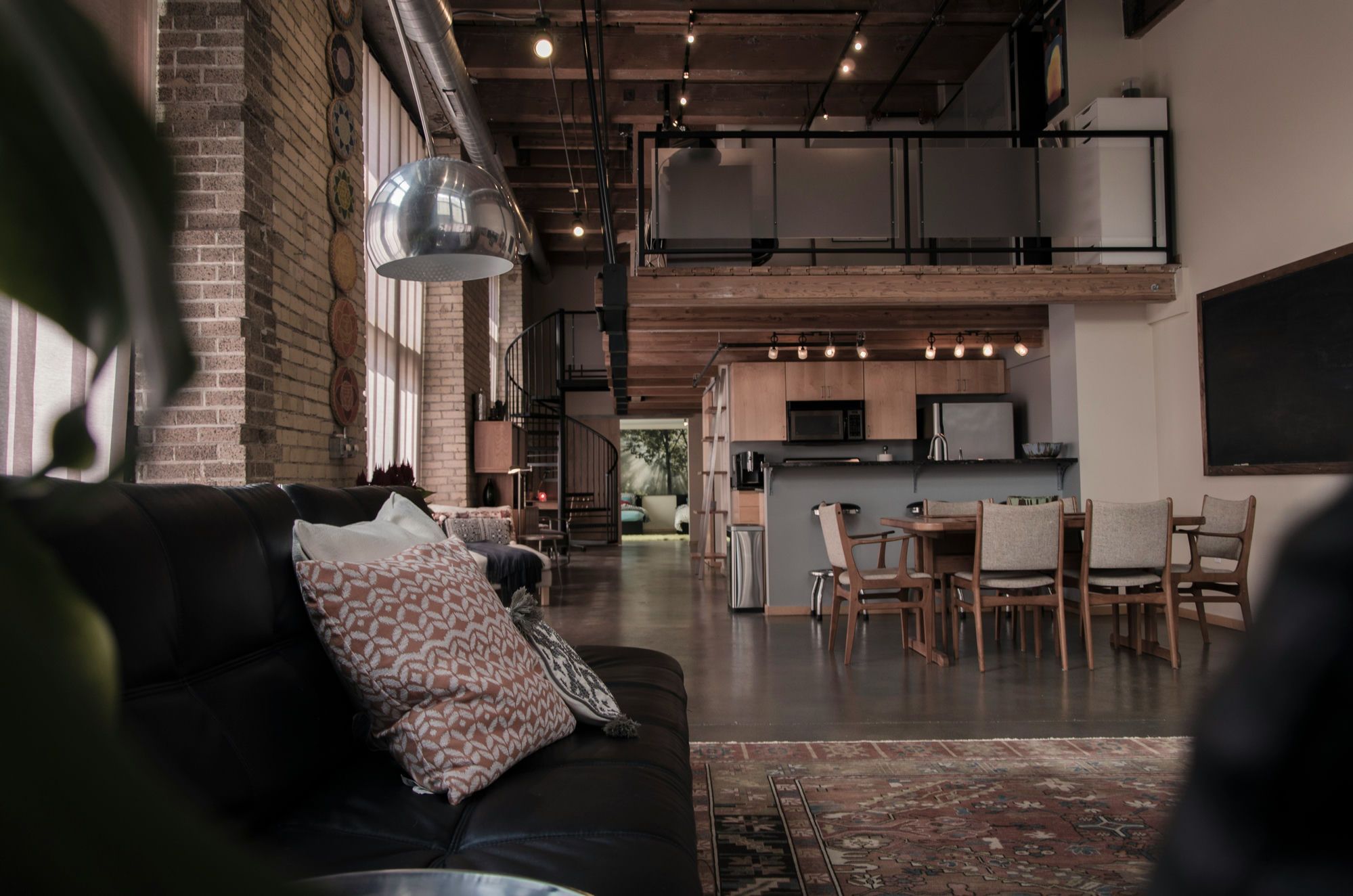 Renovated two-storey brick loft with exposed beams, spiral staircase and open kitchen