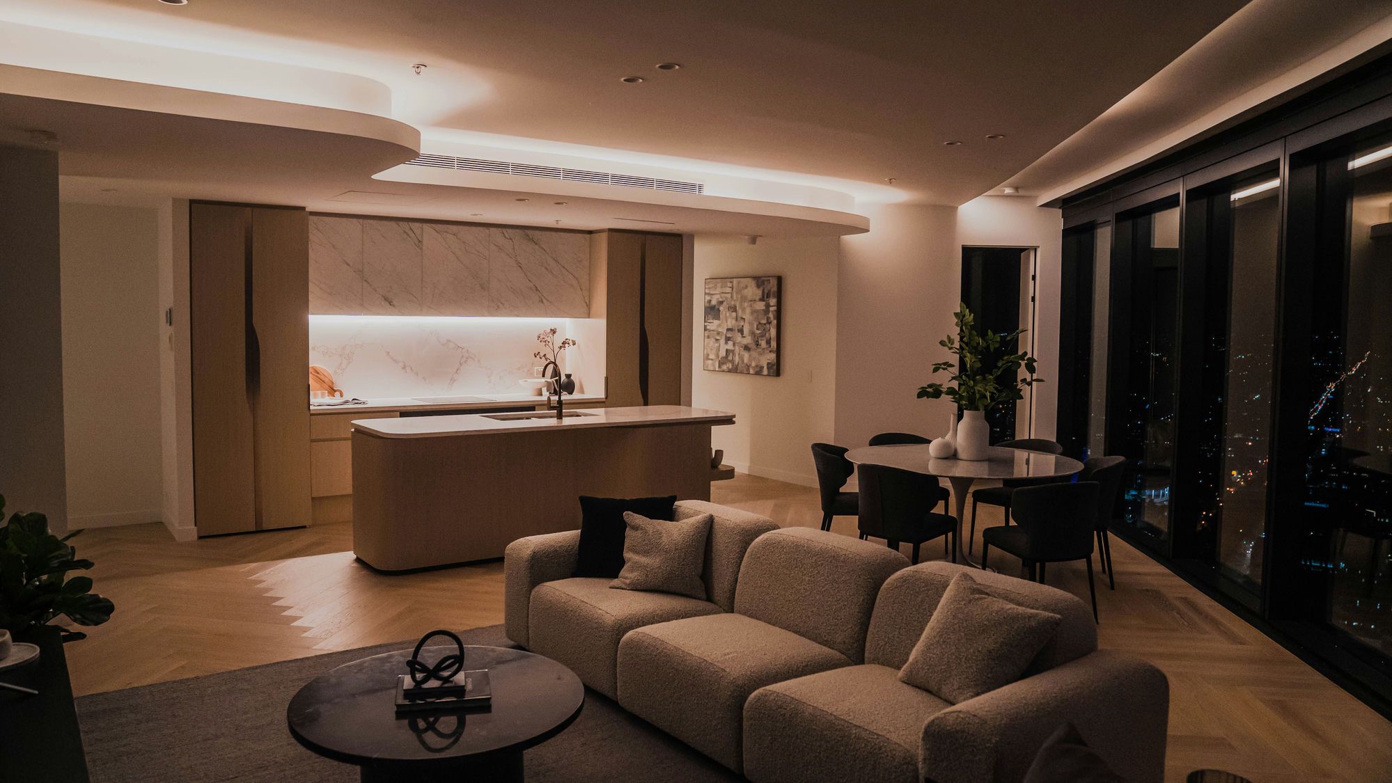 Finished Toronto condo renovation by Toronto Home Renovation — open-concept living room and kitchen at night with skyline views